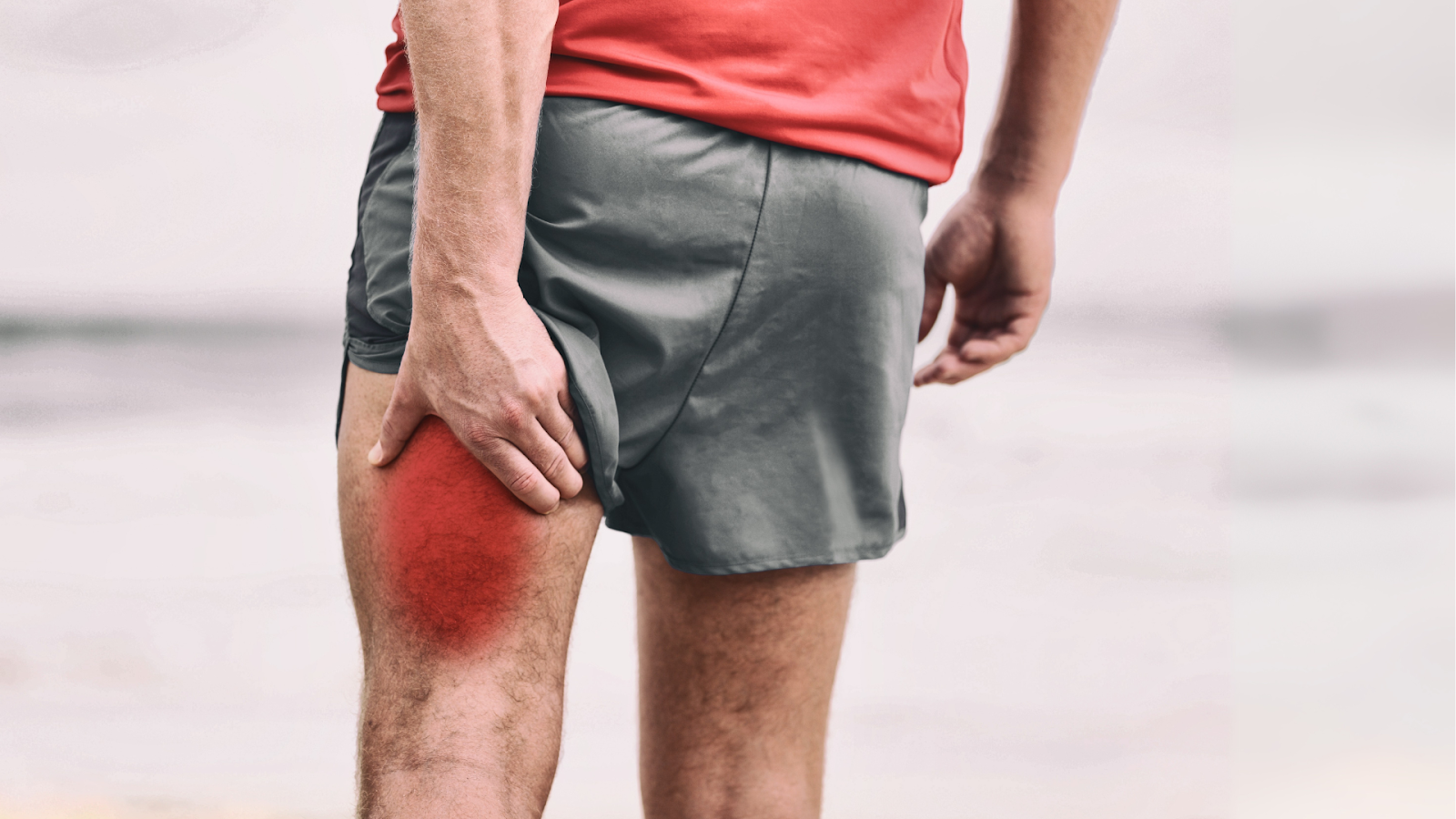 Man clutching his hamstring while jogging, experiencing acute muscle strain that may require physiotherapy.