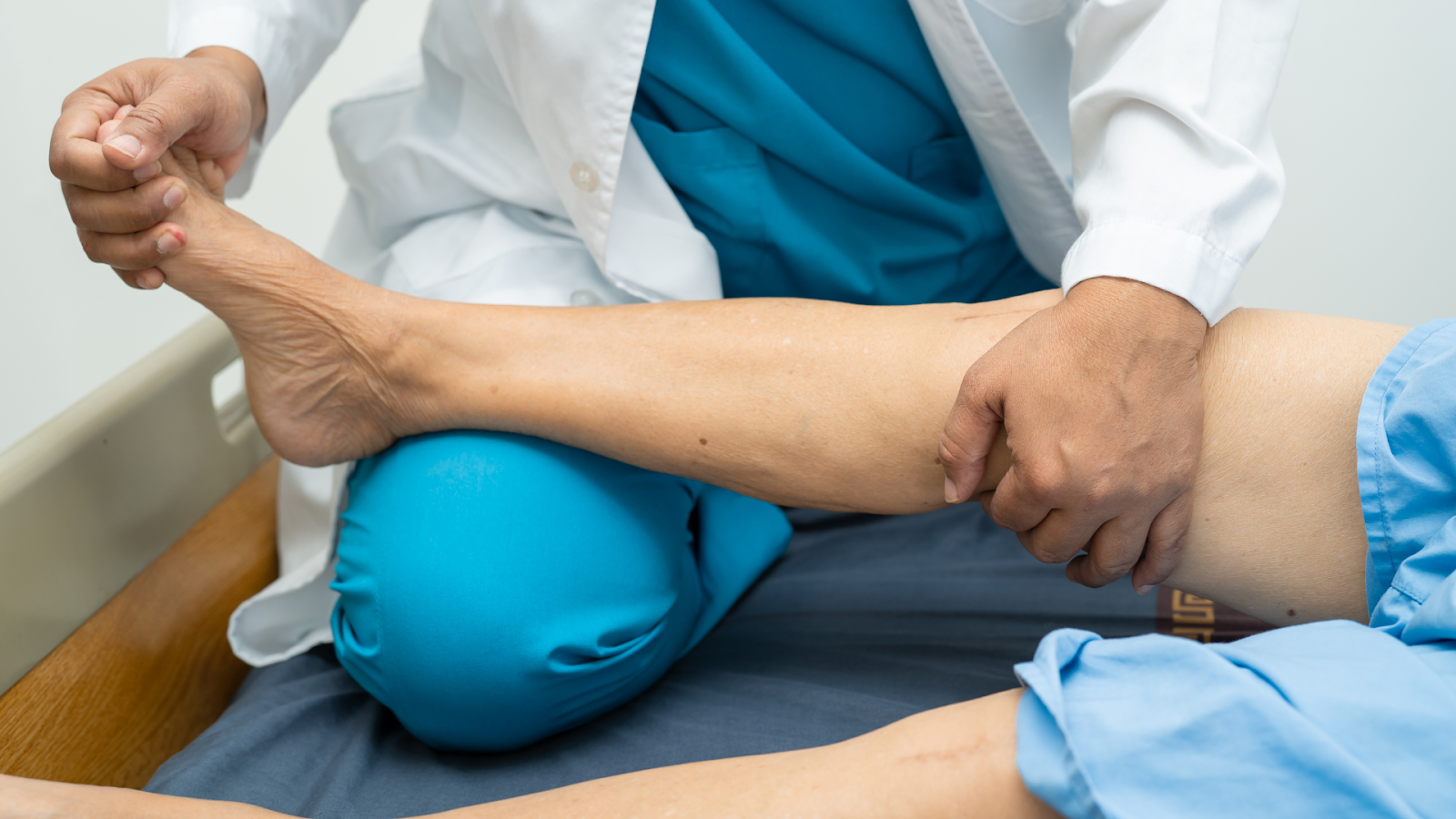 Close-up of a physiotherapist stretching a senior’s leg during a joint mobility rehabilitation session.