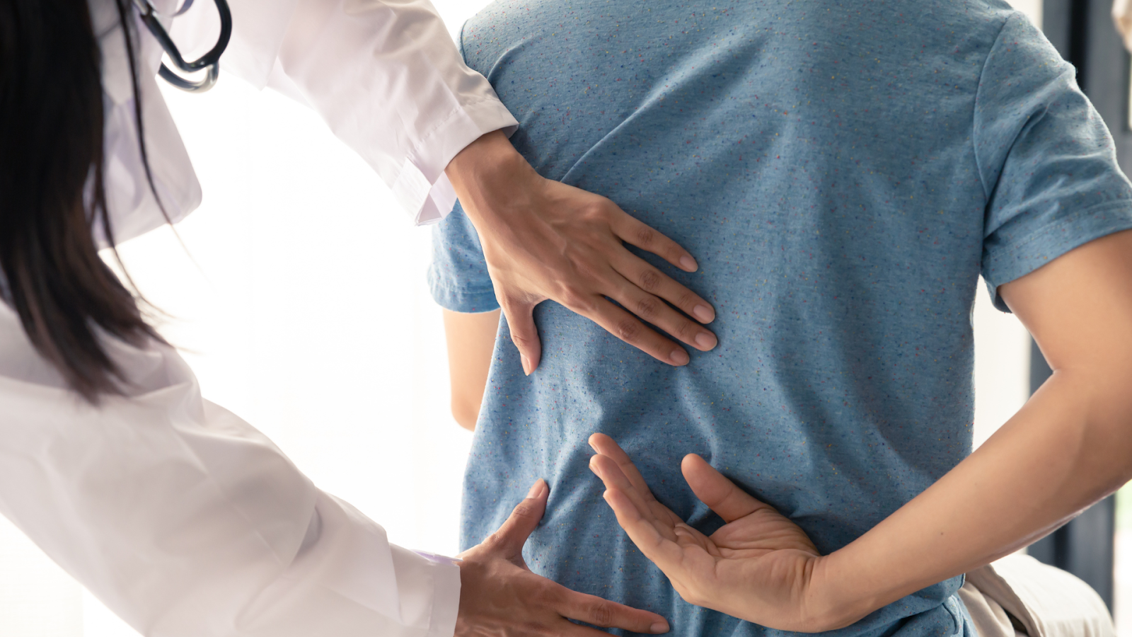 Physiotherapist assessing lower back pain in a patient during a consultation in Singapore