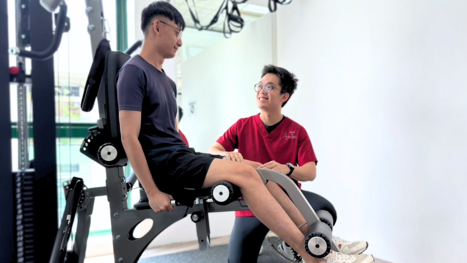 Physiotherapist guiding a patient through leg strengthening exercises on gym equipment