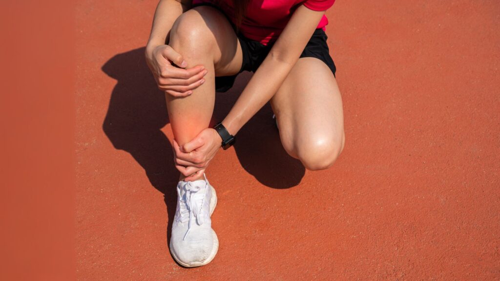 Runner clutching her lower leg in pain