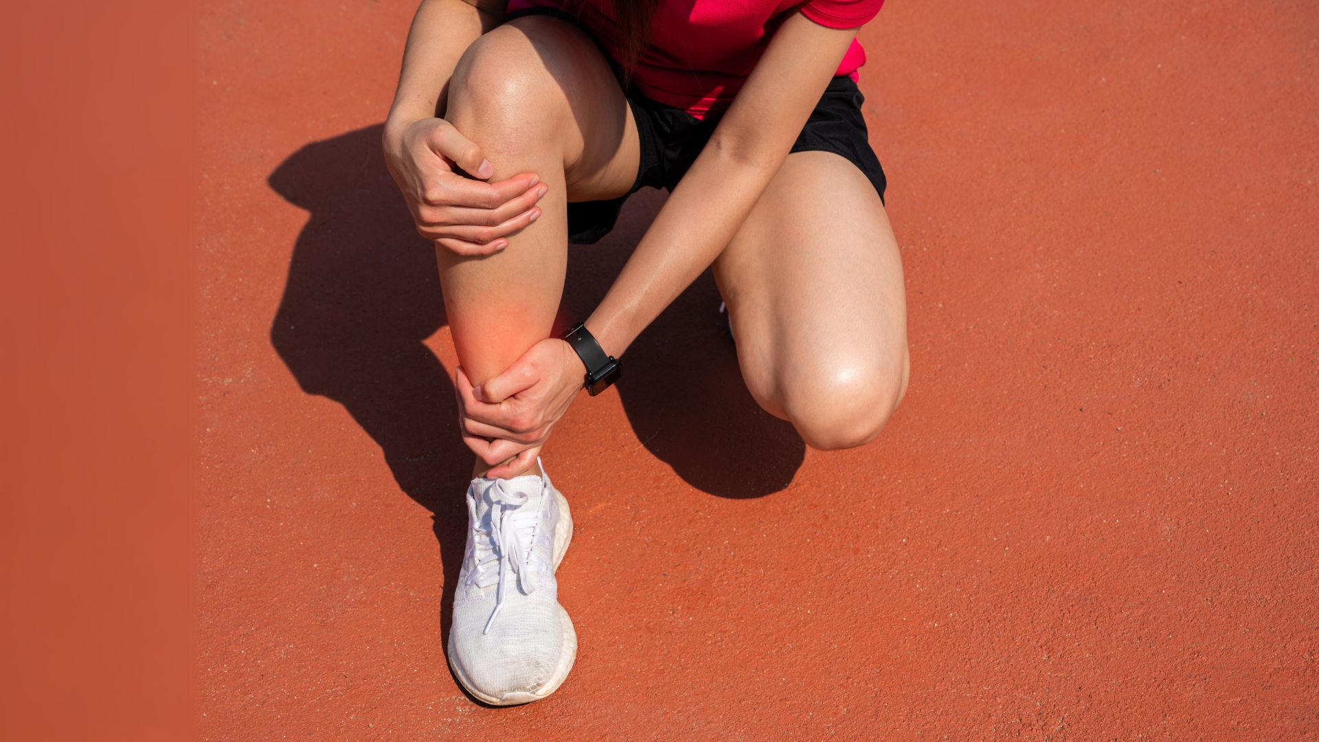 Runner clutching her lower leg in pain
