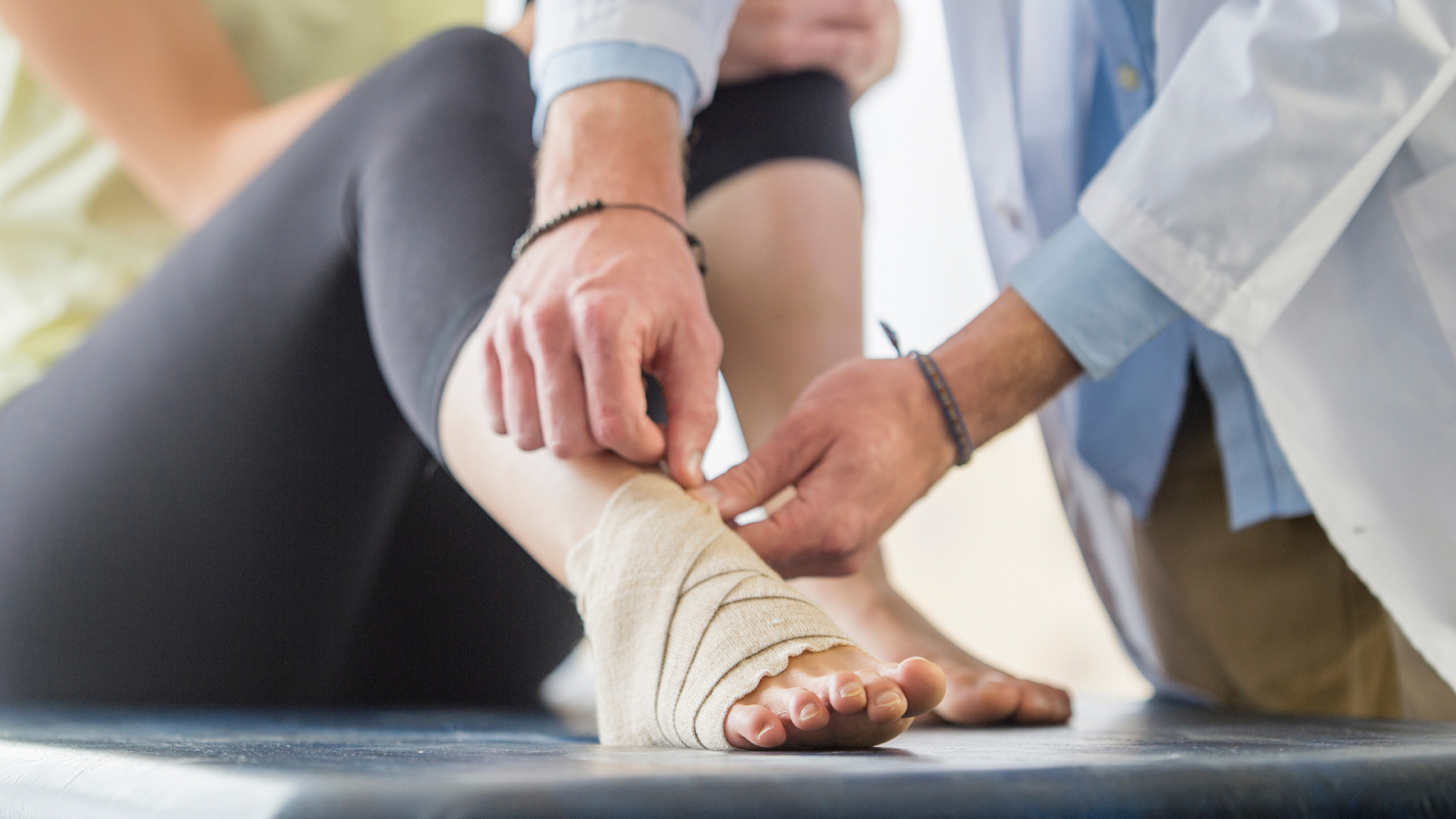 Healthcare professional wrapping an injured ankle with bandage for support.