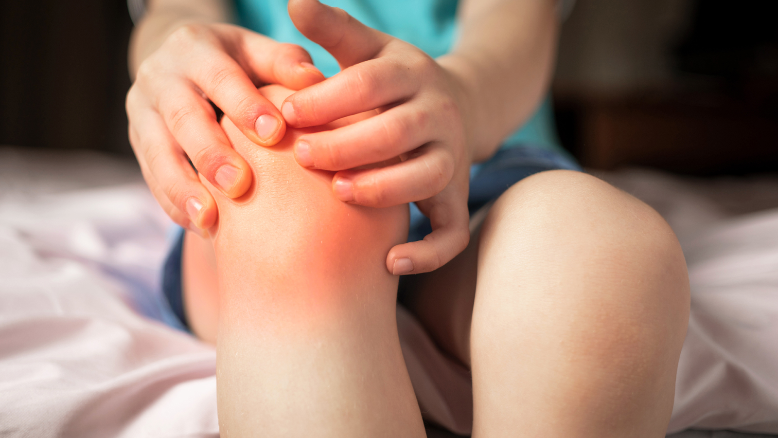 Child clutching a painful, red knee – a typical presentation of Osgood-Schlatter’s Disease.