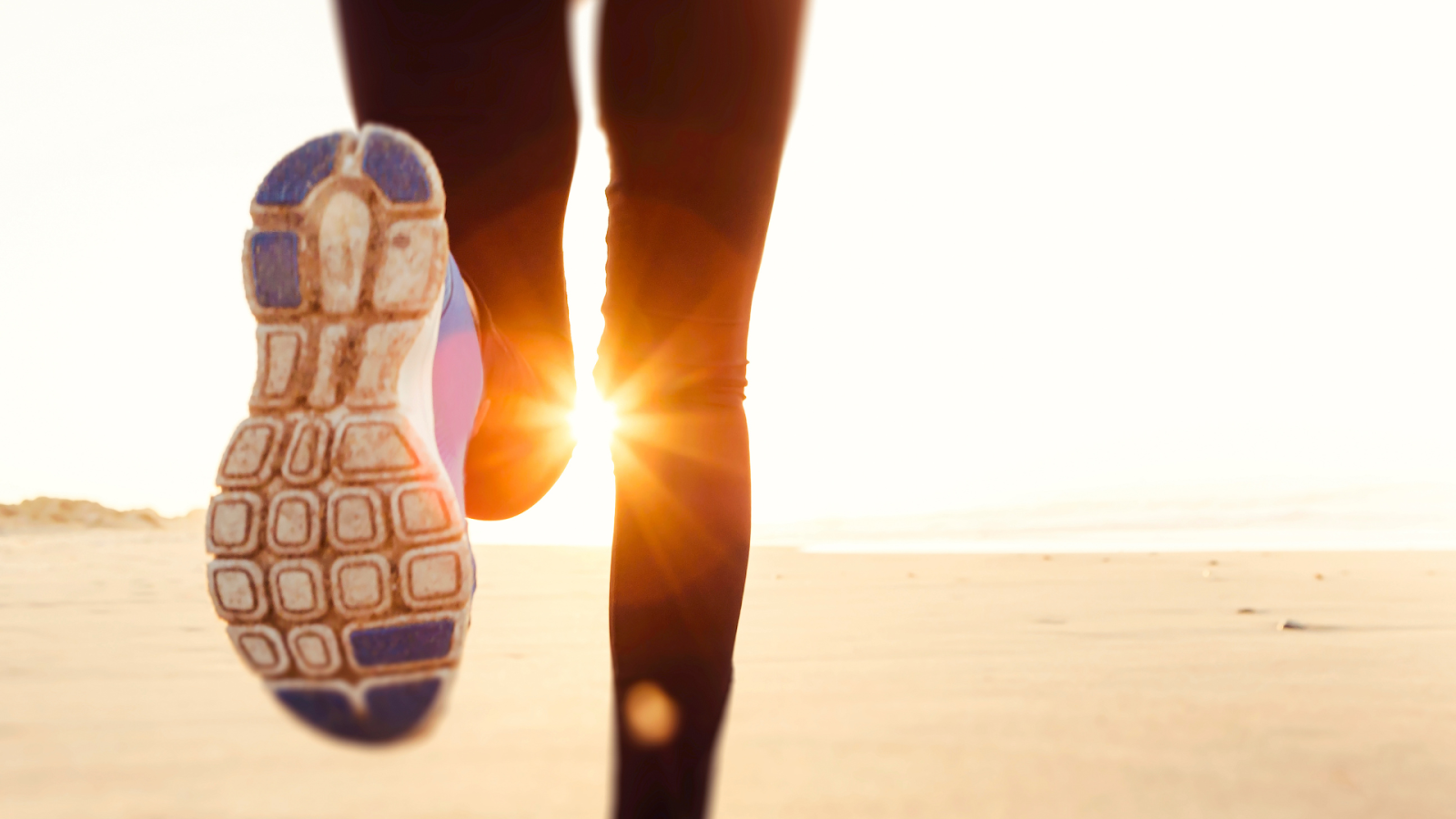 Close-up of running shoe on beach, symbolising proper footwear for preventing stress fracture during exercise.
