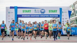 Runners at the starting line of the Standard Chartered Singapore Marathon, including adults and children in sportswear, preparing to begin the race — representing the importance of marathon foot care in Singapore’s running community.