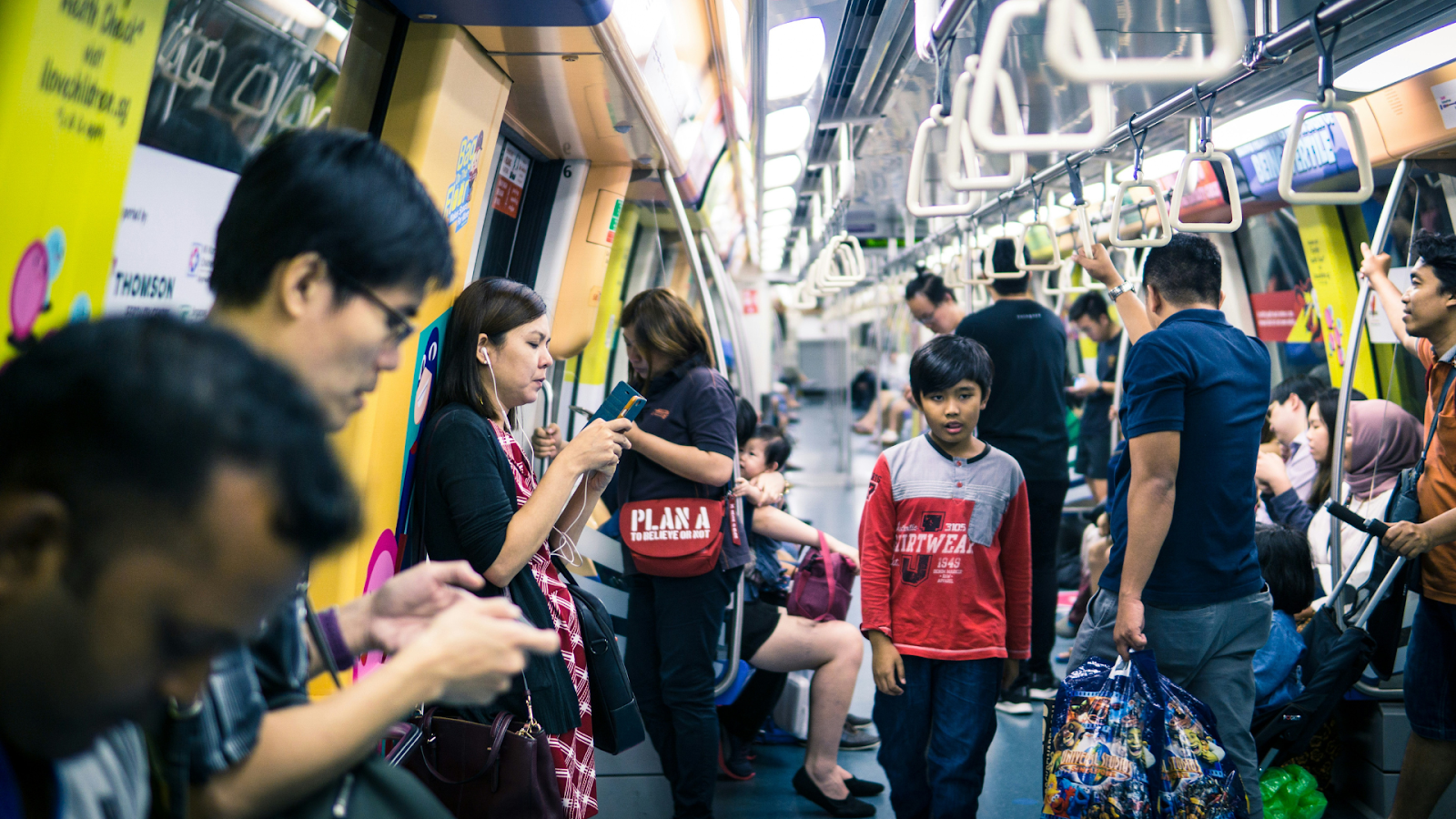 Commuters standing and sitting in a crowded Singapore MRT train.