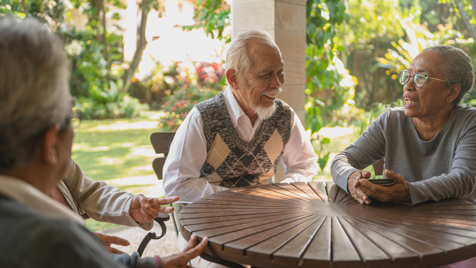 Elderly Singaporeans chatting and smiling together outdoors, enjoying active ageing and community support.