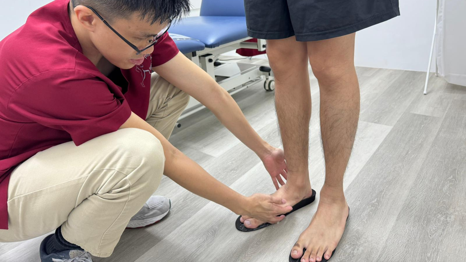 Podiatrist fitting custom insoles for a patient standing barefoot.