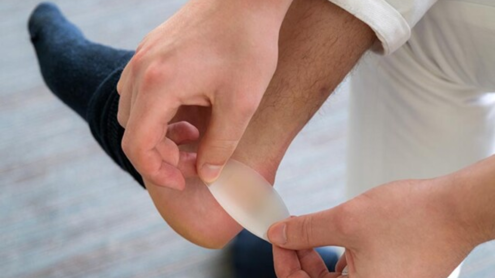 Close-up of a person applying a blister prevention pad to the heel, a common foot care strategy for marathon runners in Singapore to reduce friction and prevent injury.