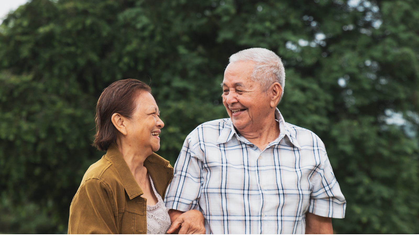 Elderly couple enjoying a walk outdoors, managing rheumatoid arthritis with an active lifestyle