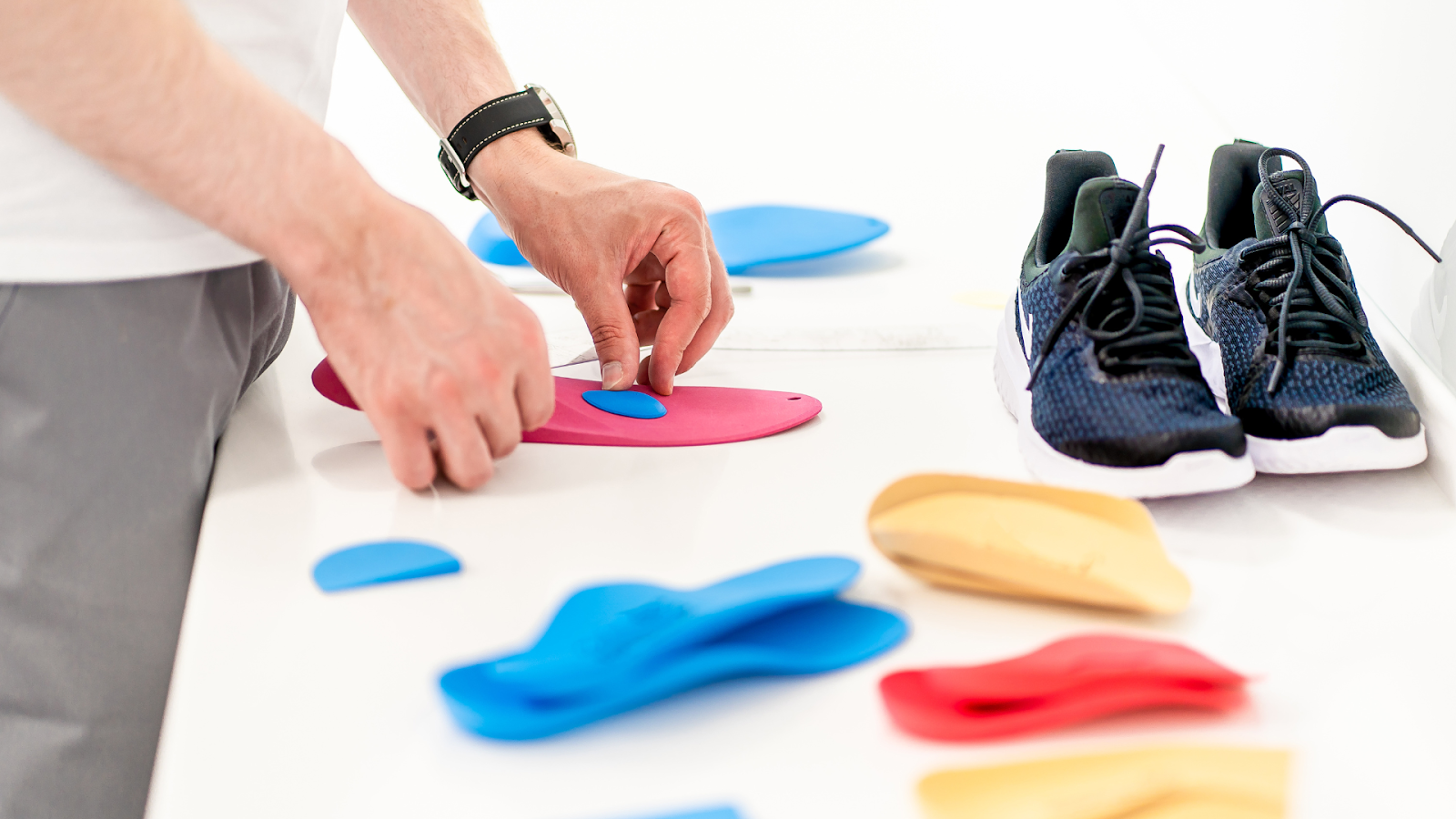Close-up of a person assembling customised orthotic insoles next to a pair of running shoes, showcasing personalised foot care solutions for marathon runners in Singapore.