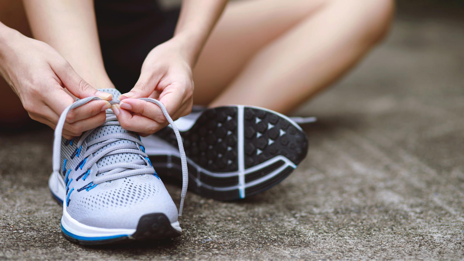 Close-up of a runner tying their shoelaces on a pair of running shoes, emphasizing the importance of proper footwear and fit for marathon foot care in Singapore.
