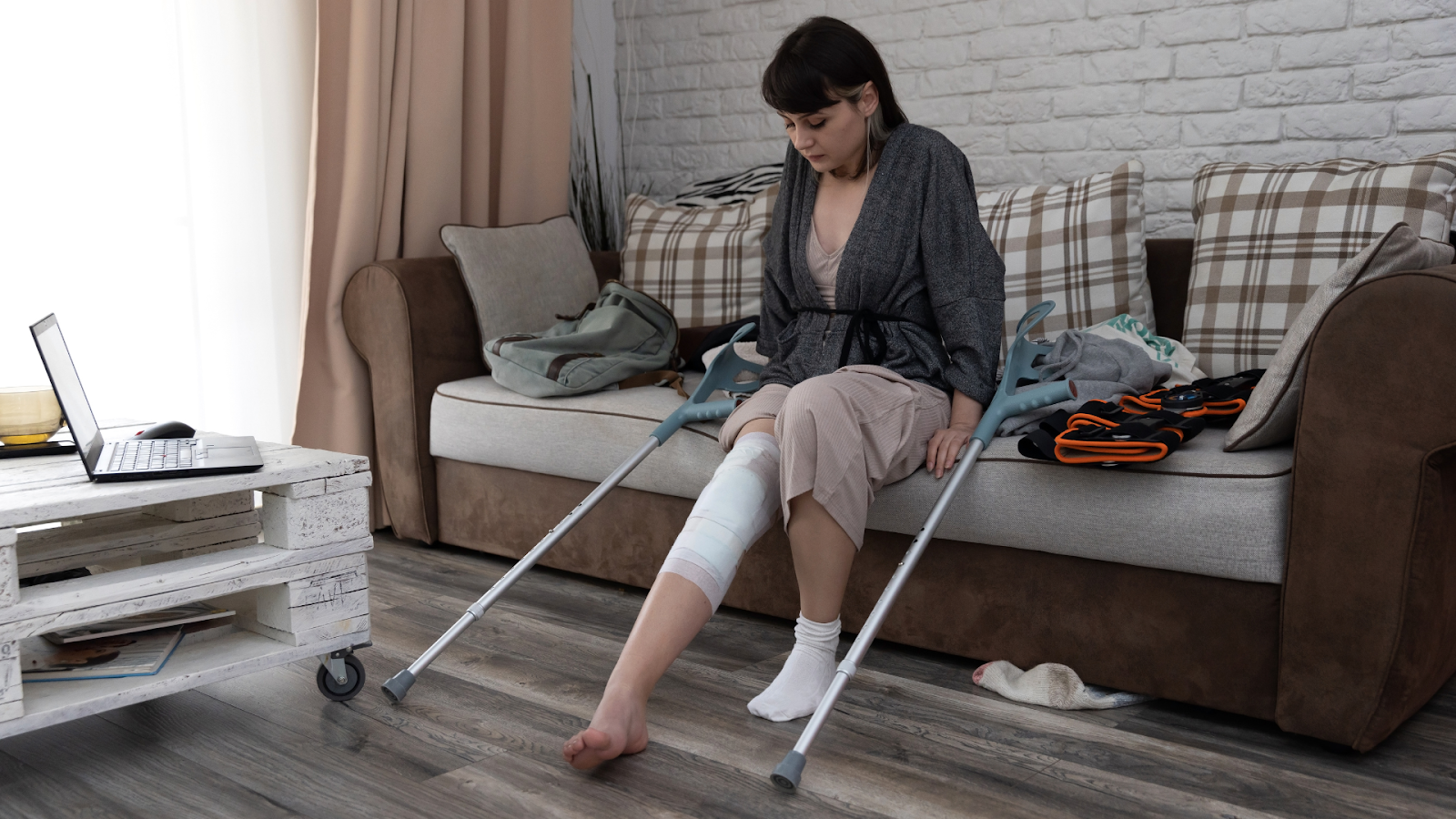 Woman using crutches at home with a bandaged leg, continuing rehab post-surgery.