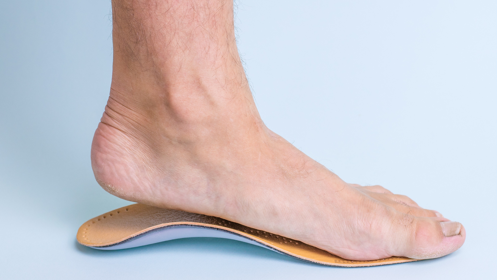 Bare foot resting on a custom orthotic insole for arch support.
