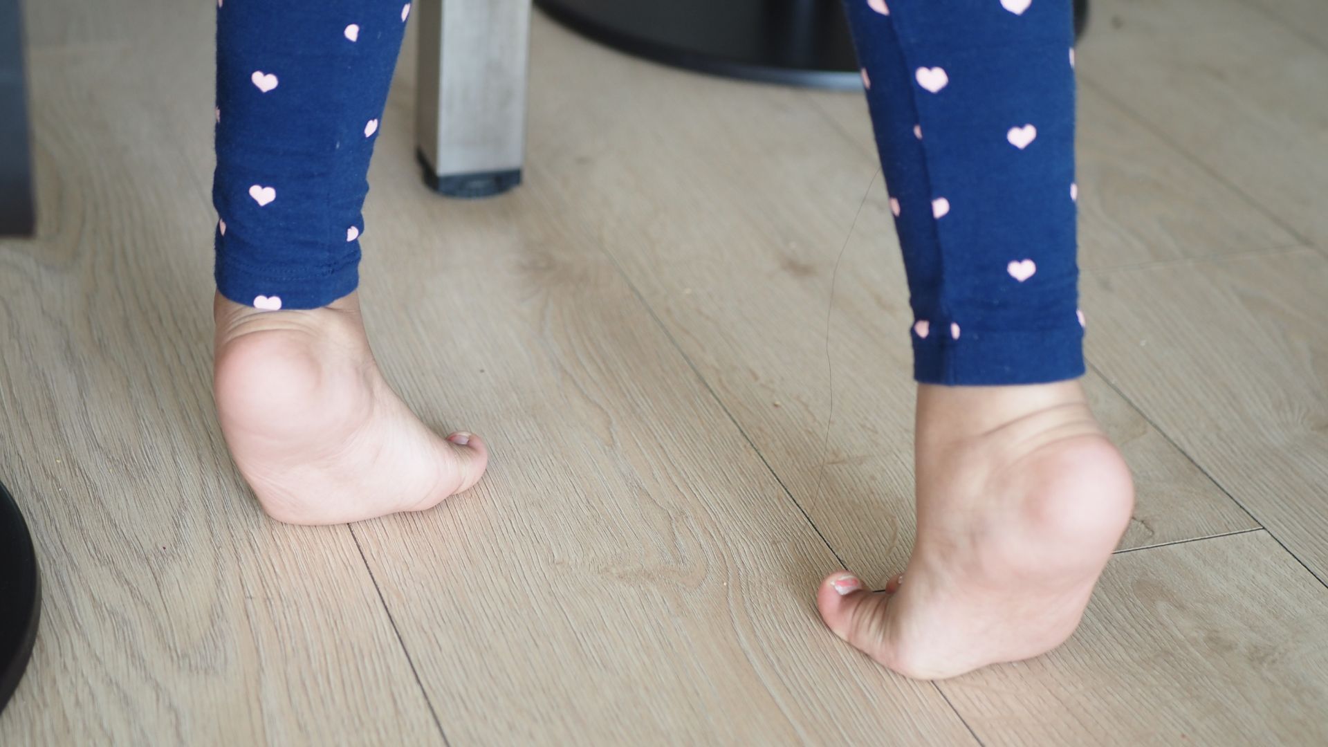 Child with pigeon toe standing on tiptoes indoors