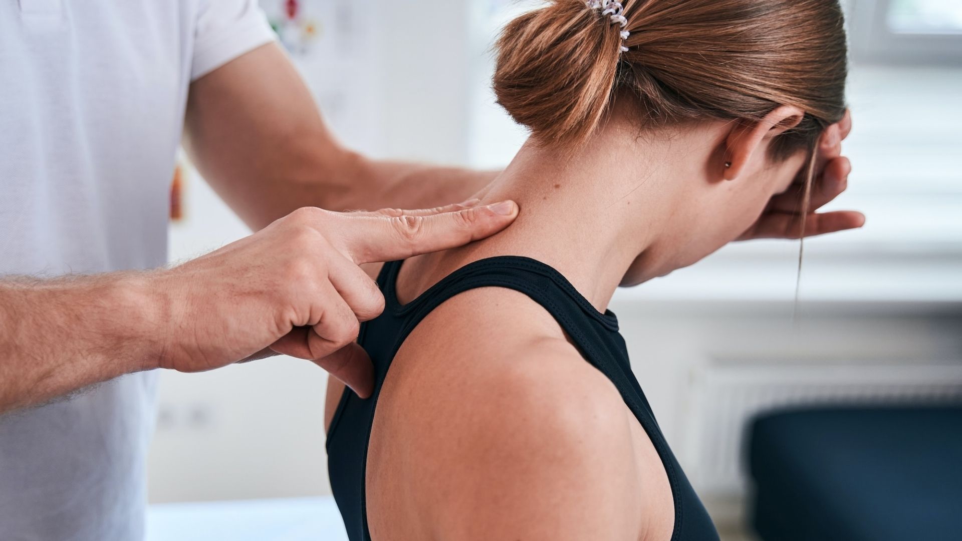 Physiotherapist applying pressure to a patient's neck trigger point, part of integrated muscle release techniques in physiotherapy.