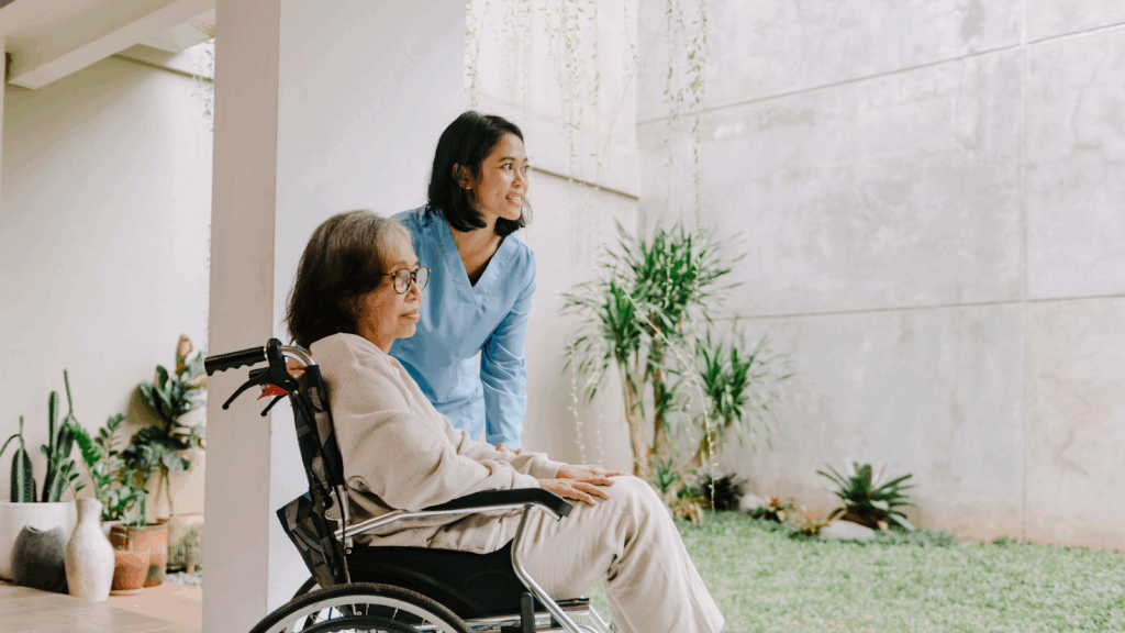 Female caregiver with elderly woman in a wheelchair outdoors