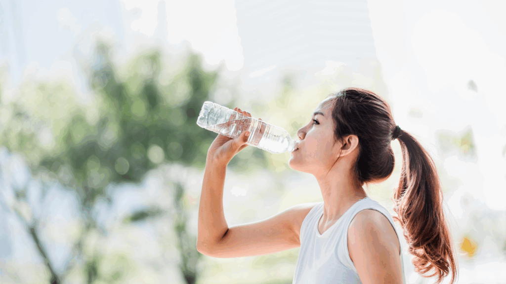 Young woman hydrating after a workout, illustrating the importance of fluid intake for muscle recovery after physiotherapy or dry needling.
