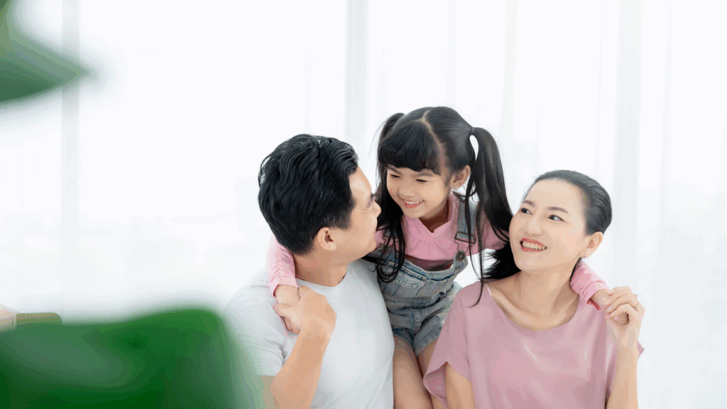Smiling Asian family with a young daughter spending quality time together at home.