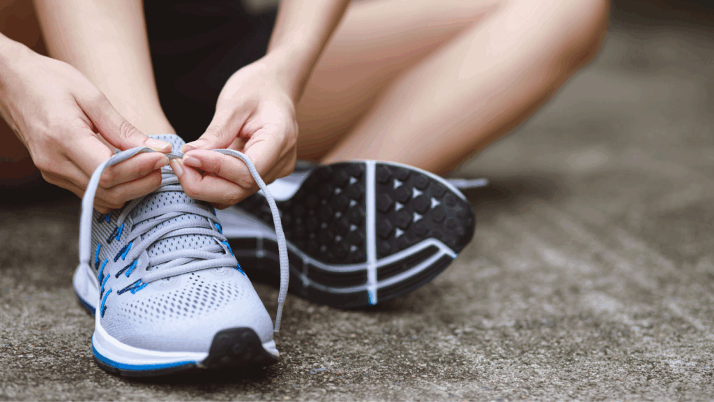 Close-up of person tying shoelaces on running shoes outdoors.