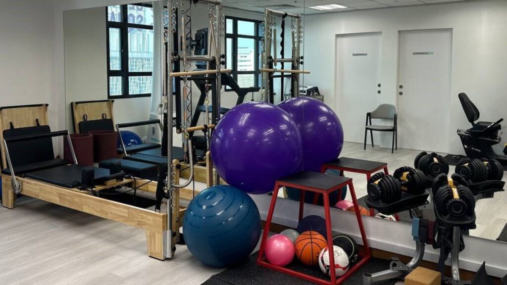 Physiotherapy gym area at Physio & Sole Clinic Tampines featuring reformer machines, exercise balls, weights, and rehabilitation equipment in a bright, well-equipped space.
