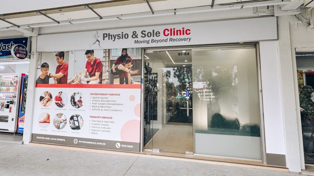 Exterior view of Physio & Sole Clinic Woodlands, featuring clinic signage, service posters, and glass entrance. The clinic offers physiotherapy and podiatry services such as sports injury rehab, custom insoles, and foot care treatments.