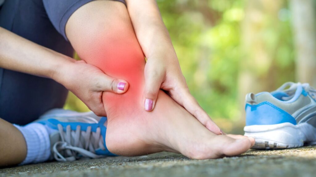 Runner holding ankle with red pain highlight, illustrating sports injury and benefits of orthotics in recovery