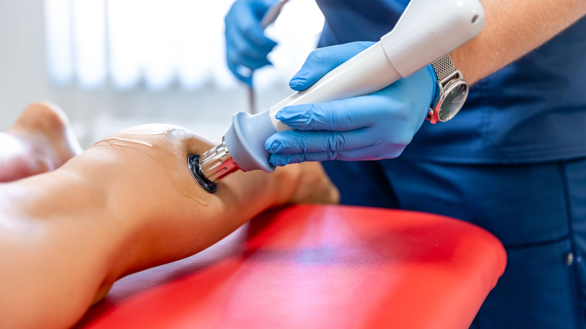 Physiotherapist applying radial shockwave therapy on a patient’s leg to relieve muscle and tendon pain.