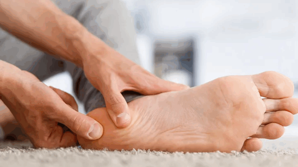 Close-up of a person rubbing their heel to relieve pain from plantar fasciitis. This condition is a common cause of foot ache after running and often leads to soreness in the heel and arch.