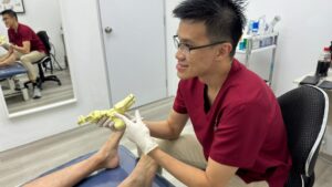 Podiatrist showing a foot model to explain bone alignment and common causes of foot pain to a patient.