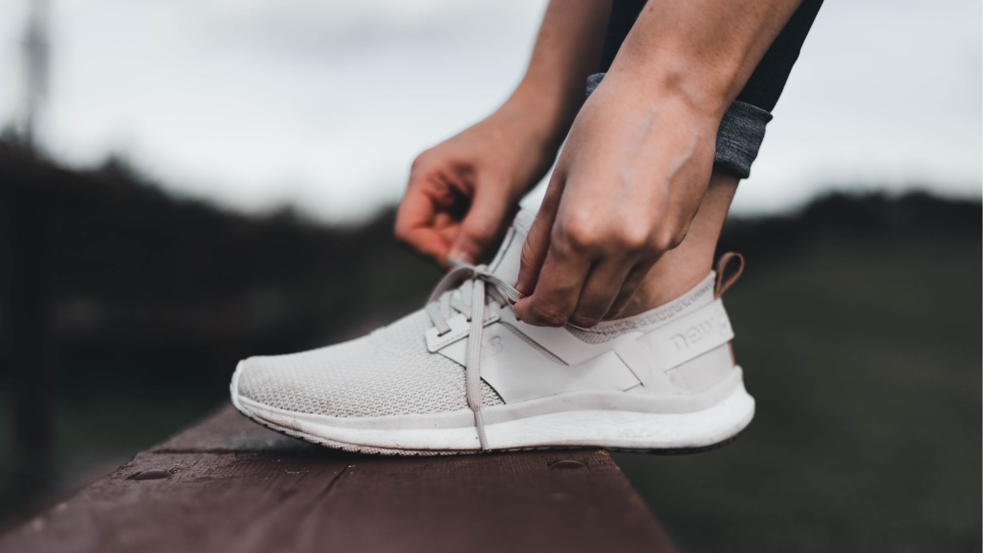 A close-up of a person tying their running shoes, highlighting the importance of supportive footwear for individuals with high-arched feet.