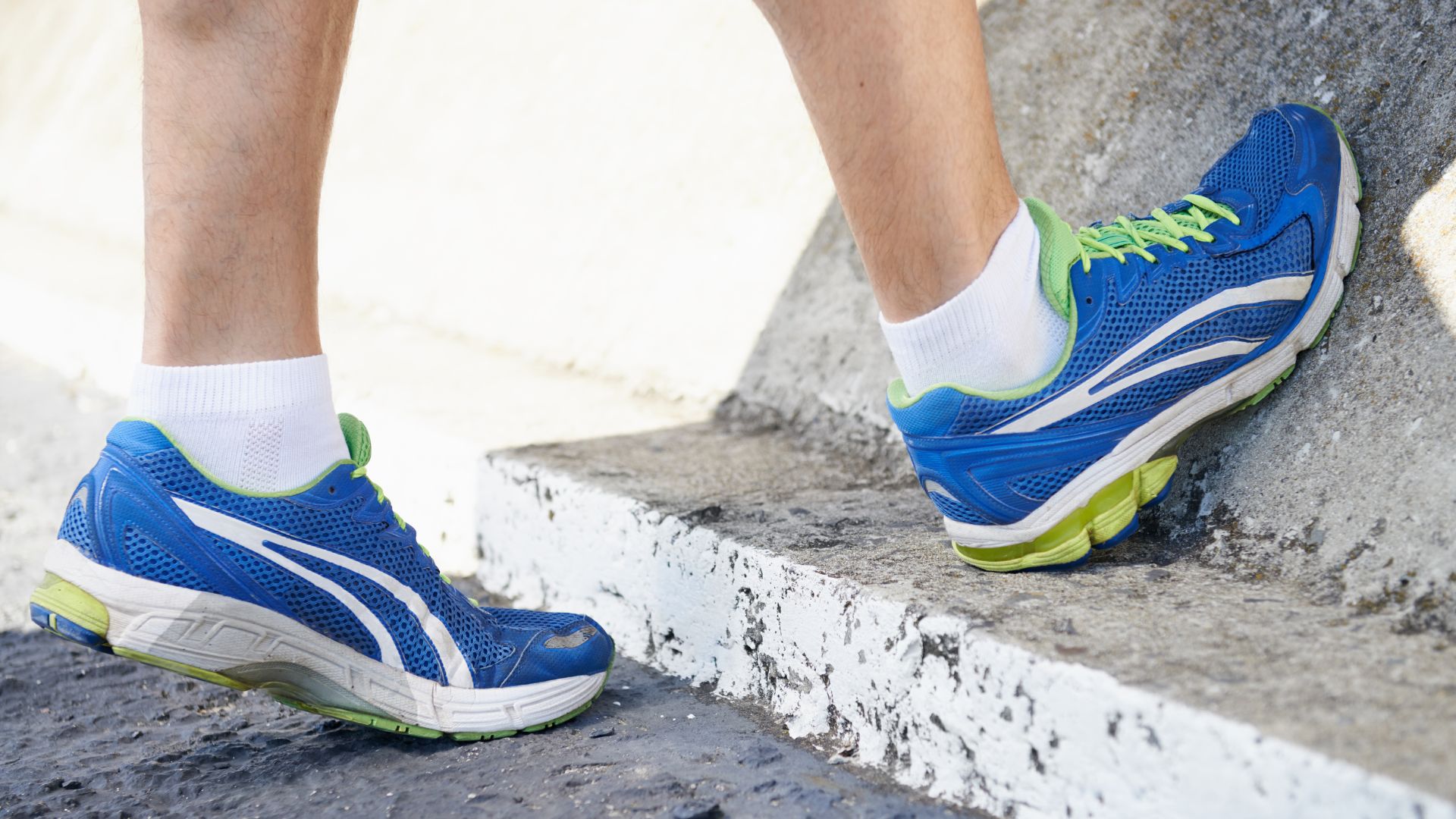 A person performing a calf stretch on a curb, demonstrating exercises that help improve flexibility and relieve tension in high-arched feet.