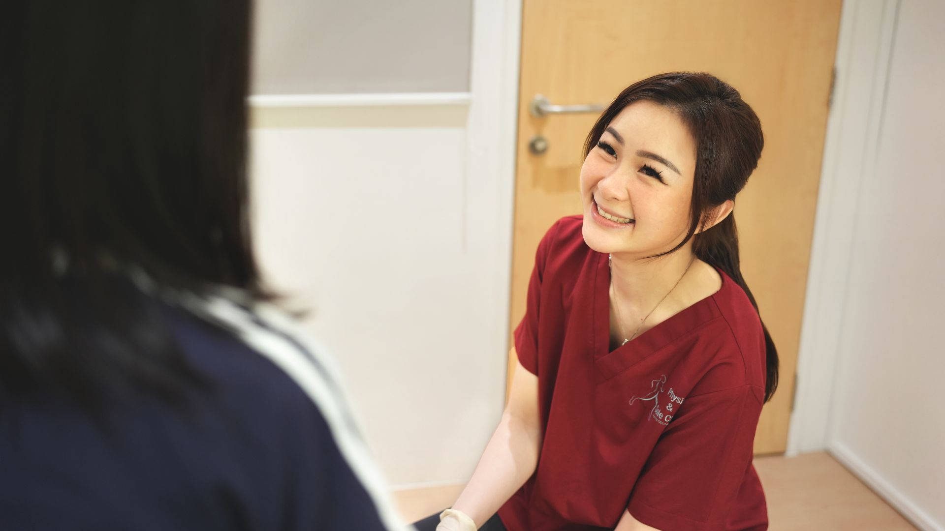 A podiatrist smiling while speaking with a patient, representing supportive and personalised care for high-arched feet and related issues.