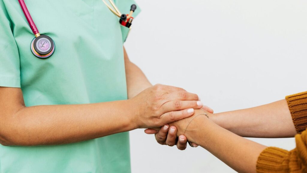 Healthcare professional holding a patient’s hand, representing trust and support in podiatric and physiotherapy care.