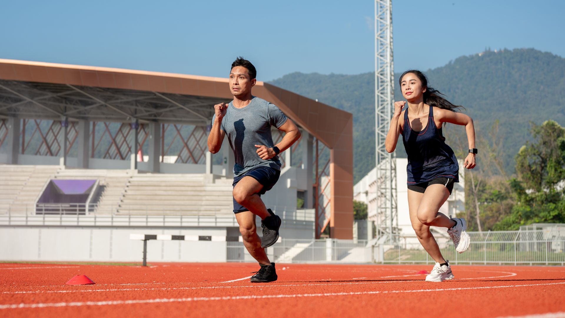 Two adults running on a track, representing how high-arched feet can affect performance and impact during sports activities.