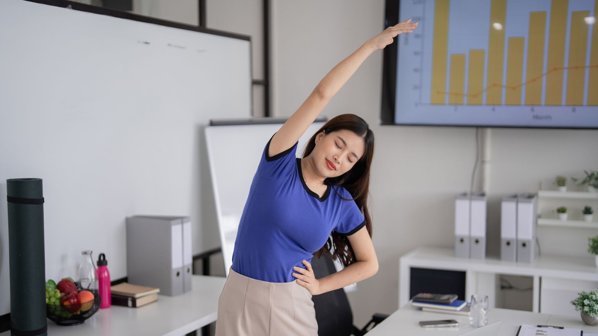 A woman in an office performing a side stretch to relieve posture-related tension and reduce workplace stiffness.