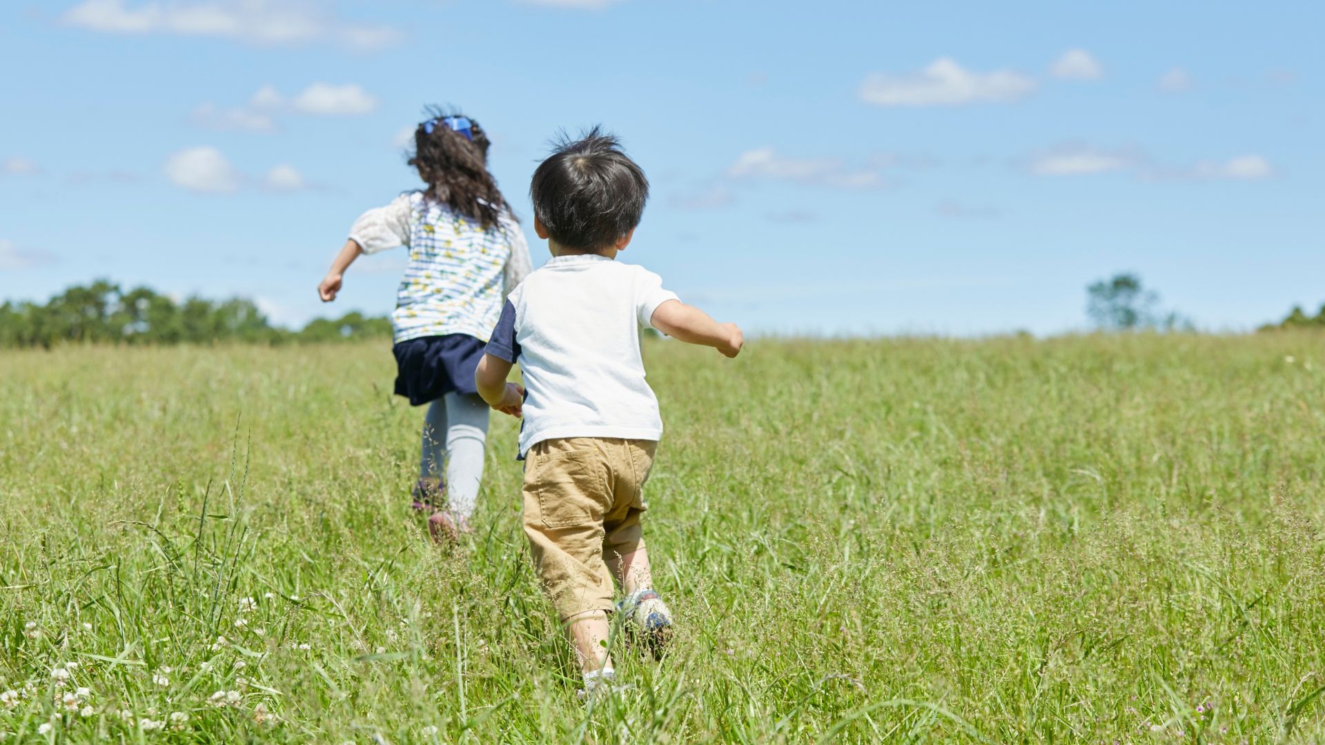 Children running outdoors in a grassy field, demonstrating natural gait and leg development.