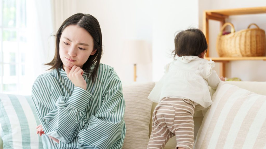Mother looking worried while her baby plays nearby, reflecting parental concerns about movement milestones and development.