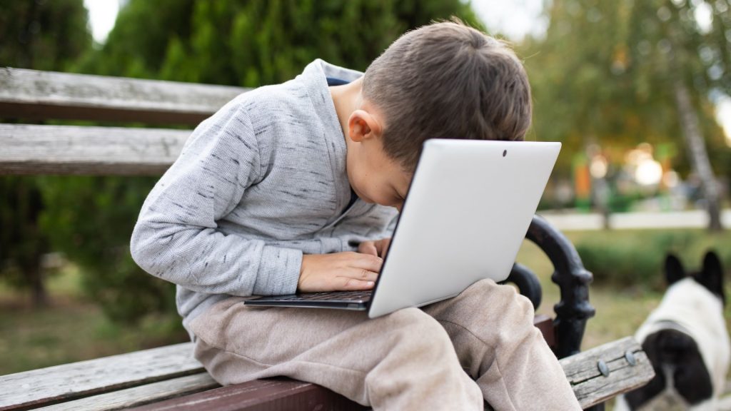 Young child sitting slouched while using a laptop, showing poor posture and core strength concerns in children.