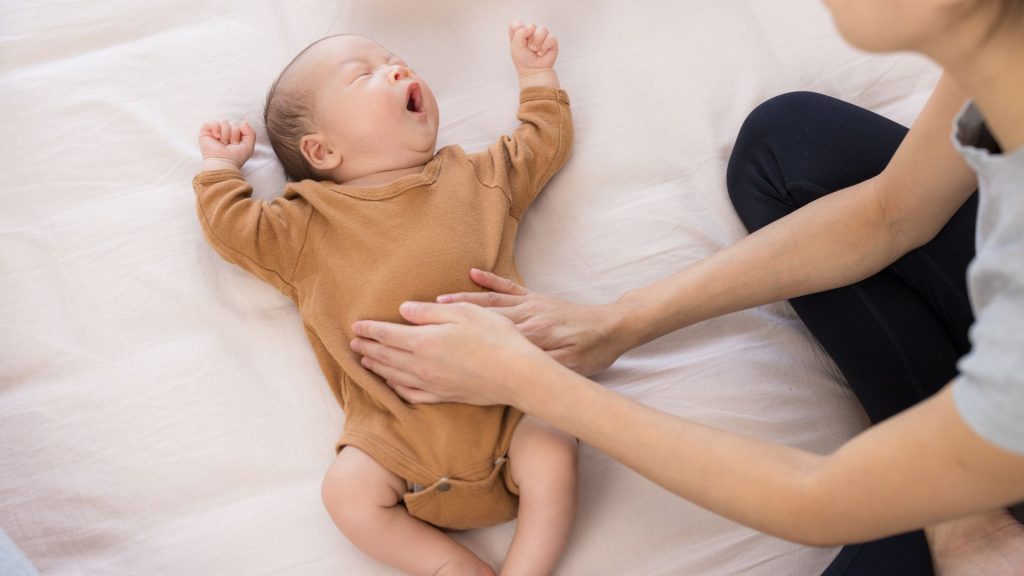 Physiotherapist gently assessing a baby’s movement and muscle tone during a paediatric physiotherapy session.