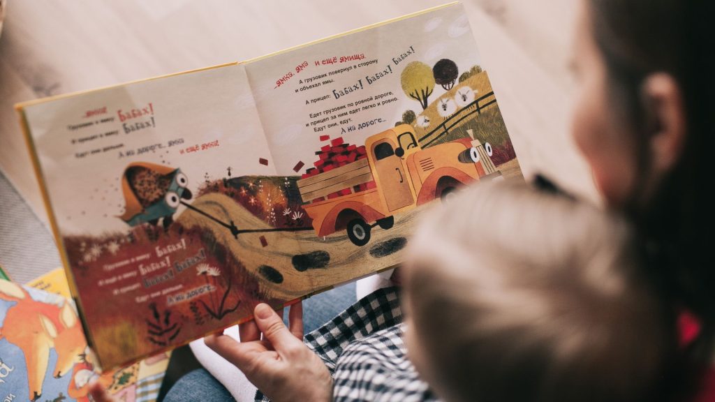 Adult reading a picture book to a young child, supporting attention, learning, and early development.