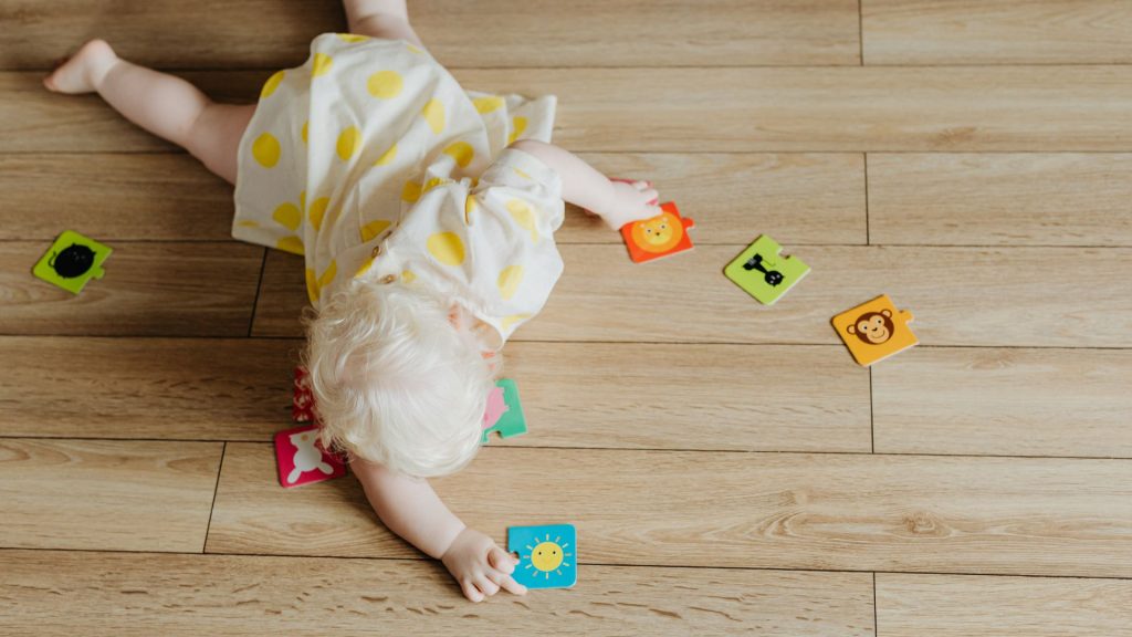Baby lying on the floor reaching for toys, developing early motor skills and coordination during play.