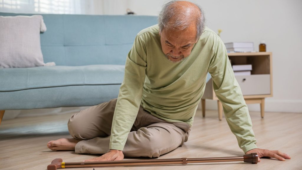 Elderly man on the floor using a walking aid, showing how foot and nail problems can affect balance and mobility