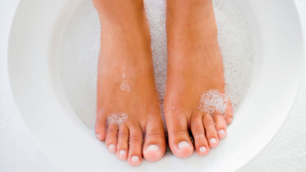 Feet soaking in warm water as part of foot hygiene and nail infection prevention routine