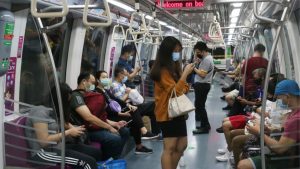 Office commuters standing and sitting inside a Singapore MRT train, illustrating prolonged time spent in enclosed footwear during daily travel.
