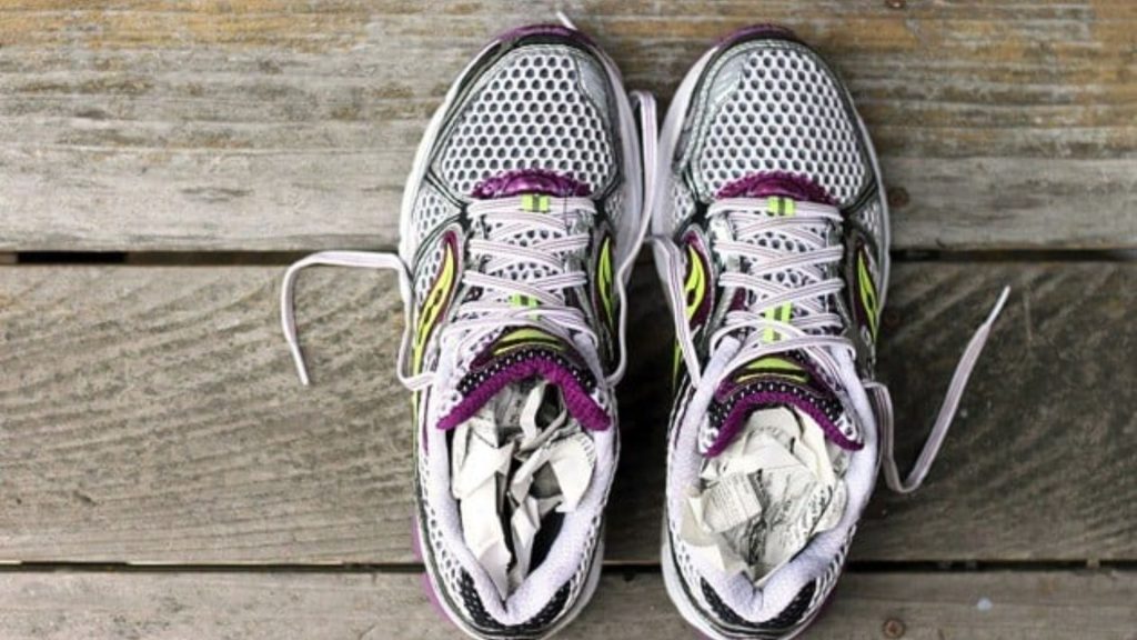 Running shoes placed out to dry with paper inside, illustrating the importance of allowing footwear to dry fully between uses.