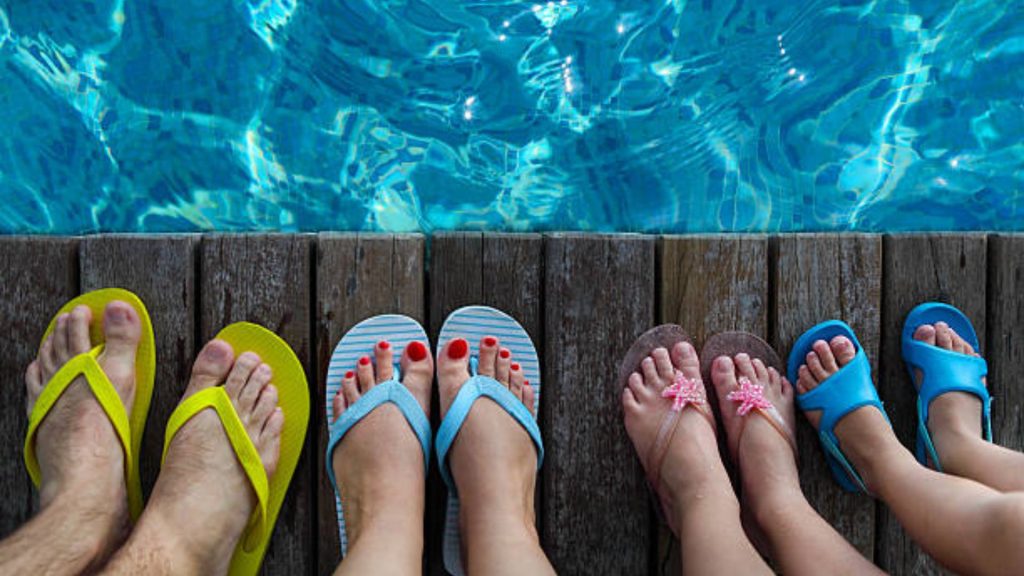 People wearing flip-flops standing by a swimming pool deck, highlighting shared wet environments that can increase fungal exposure risk