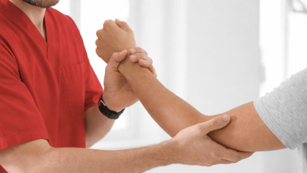 Physiotherapist assessing elbow pain by examining a patient’s elbow.