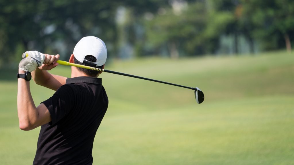 Golfer following through on a swing, highlighting repetitive elbow and forearm movement linked to golfer’s elbow.